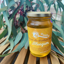 Load image into Gallery viewer, The Gathered Bowl 's delicious Bluegum Honey is sitting on natural slatted wooden bench with bluegum leaves in the background